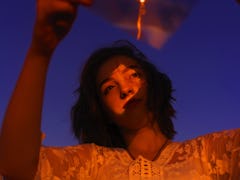 Young Woman Looking Away While Holding Plastic With Reflection On Face Against Sky