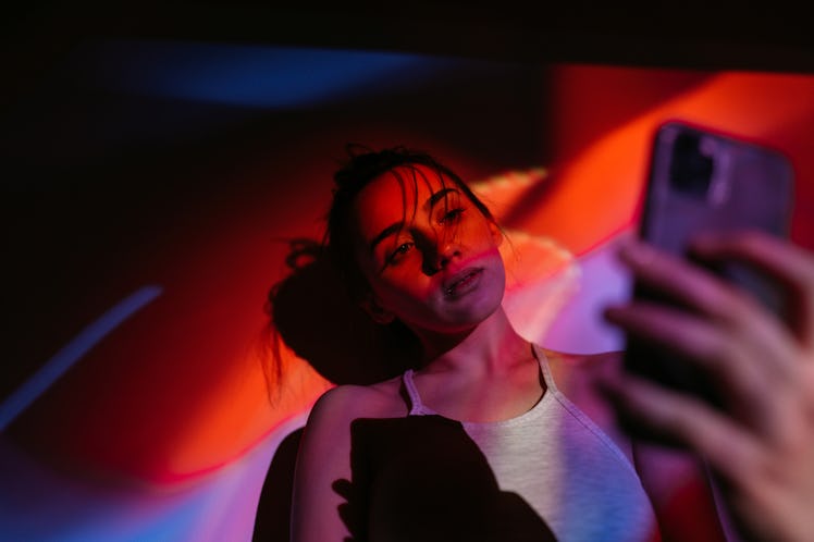 Young woman taking selfie in neon lighting