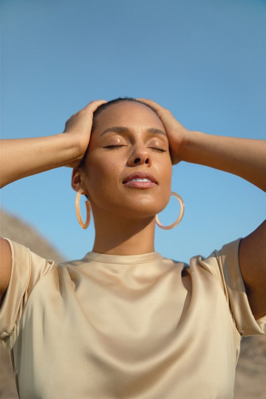 A portrait of Alicia Keys, who is finally choosing self-care, with closed eyes in a beige shirt and ...