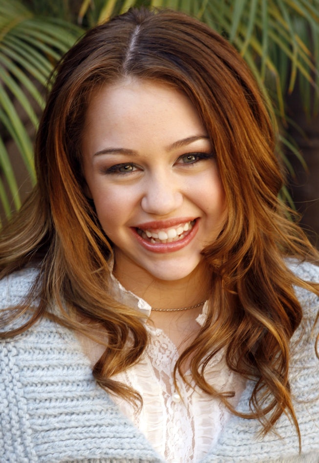 A young Miley Cyrus with curly brunette hair
