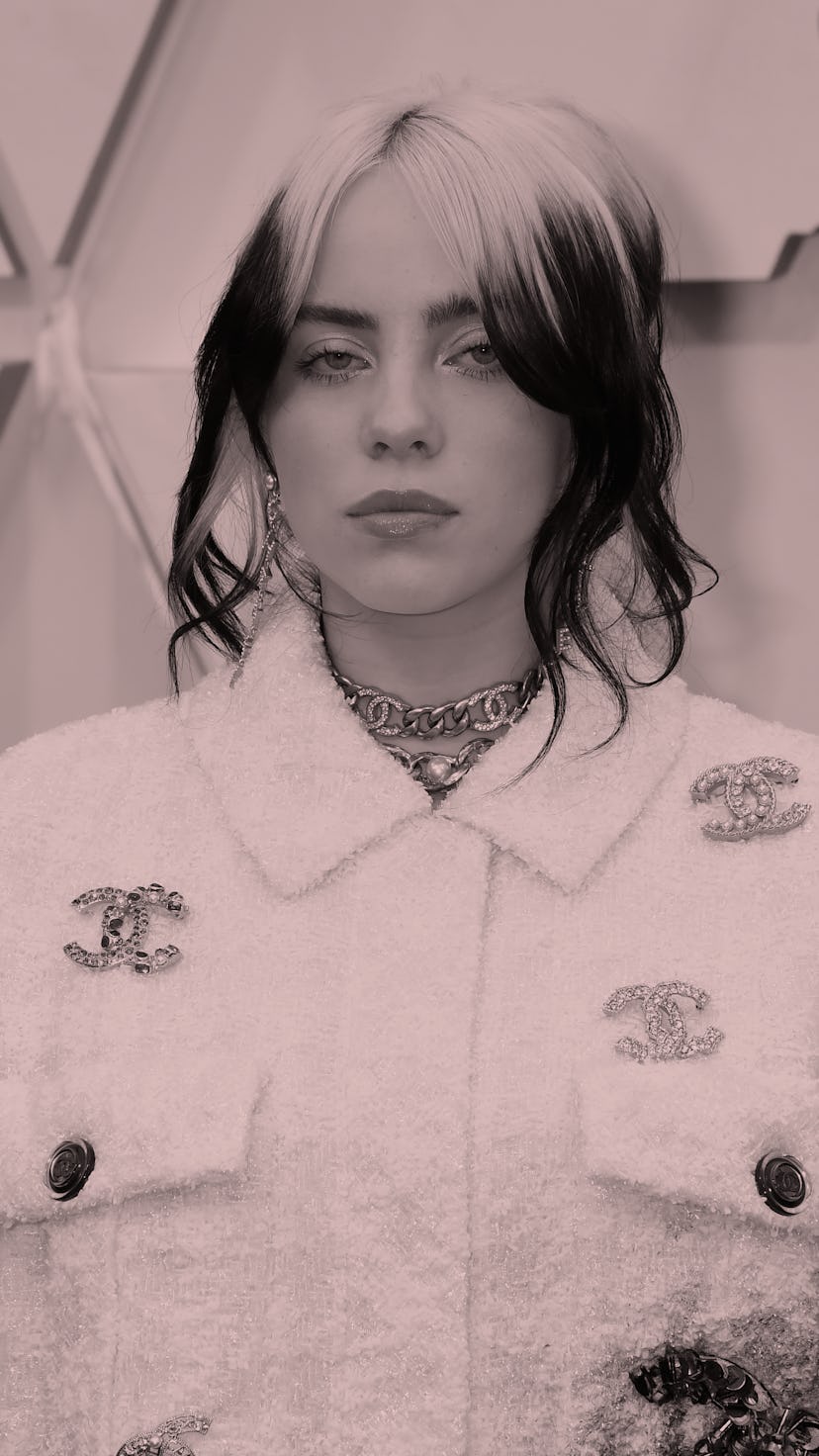 Billie Eilish, with black and green ponytail, holds hands up, showing off black manicure