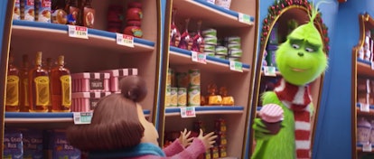 The Grinch holds a jar of jam and smiles in a store in Whoville.