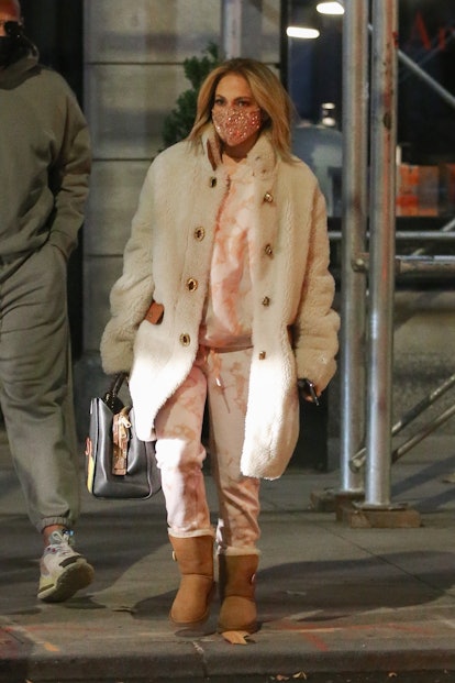 Jennifer Lopez in a white-peach tracksuit, beige teddy coat and brown Ugg boots, and a peach sequin ...