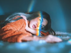 Woman Lying Down On Bed With Rainbow On Face