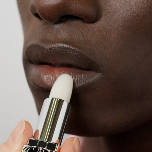 A model applying the Dior lip balm 