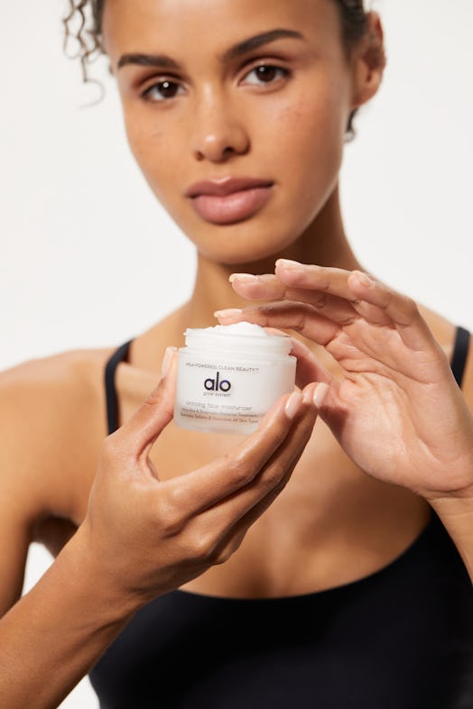 Model holding the facial moisturizer from Alo Yoga's new beauty line.