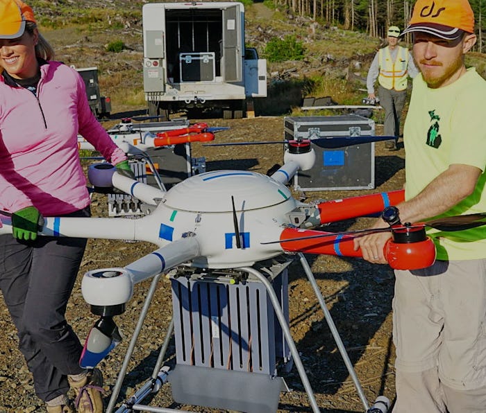 Two workers carrying a DroneSeed drone.