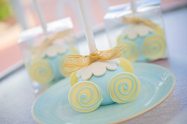 A blue and yellow 'Cinderella' carriage cake pop sits on a blue plate at Disney. 