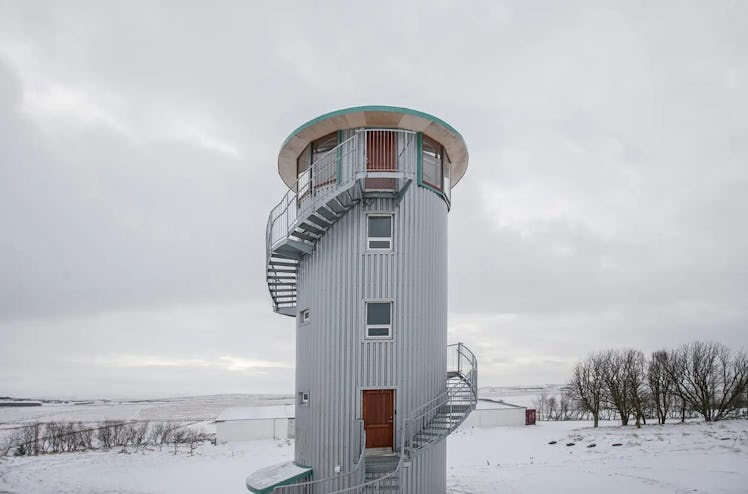 An apartment within a tower is surrounded by snow in the winter. 