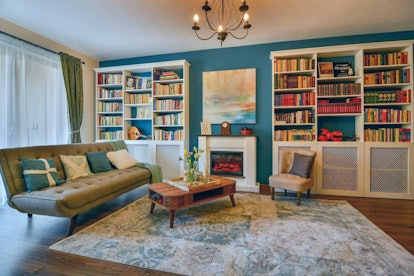 A living room within an Airbnb apartment has charming blue walls and books.