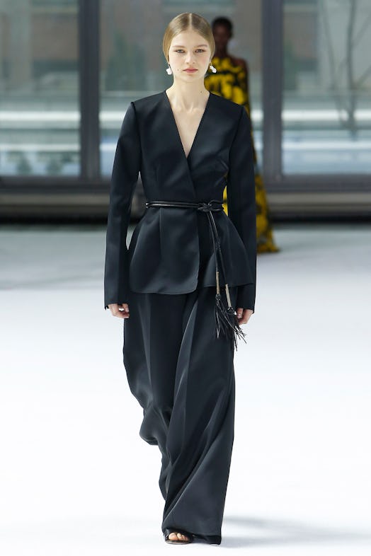 A model walking the runway in a black satin oversized suit from Carolina Herrera Fall/Winter 2020 co...