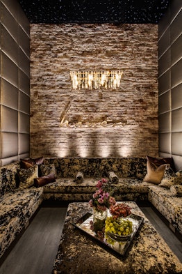 The interior of Haven Spa NYC features a luxurious couch, chandelier, and stone wall.