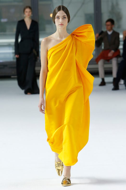 A model in an orange one-shoulder dress from Carolina Herrera Fall/Winter 2020 collection.