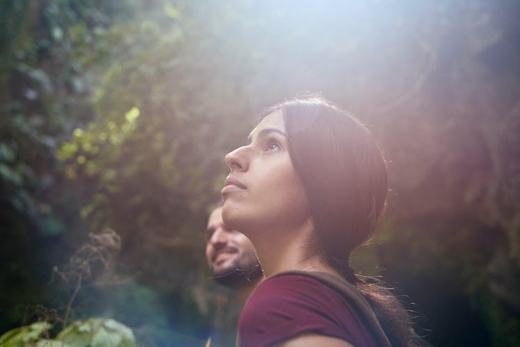 Young woman and young man looking at sun in forest