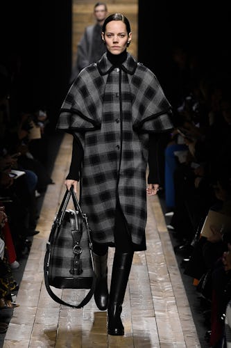 A model walks the runway in a black-and-grey checkered trench coat with a matching bag from Michael ...
