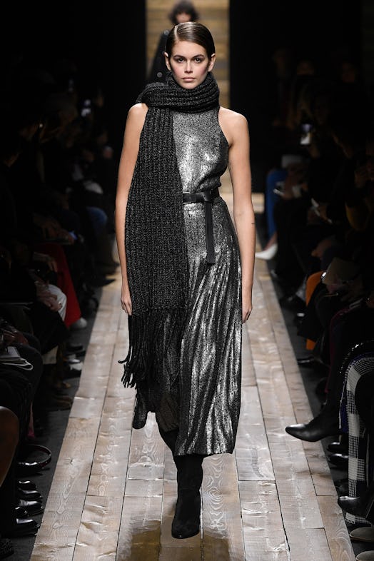 Kaia Gerber walks the runway of the Michael Kors Fall Show in a grey glittery pleated skirt with a l...