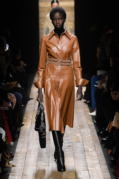 The model wears a brown leather pleated dress from Michael Kors Fall 2020 Collection.