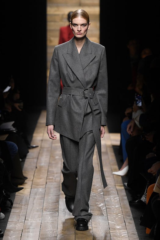 A model walks the runway in a grey belted suit from Michael Kors Fall 2020 Collection.