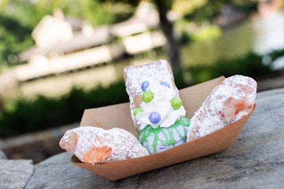 Three beignets covered in powdered sugar sit on a rock at Disney for the Disney Villains After Hours...