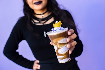 A woman dressed in all black holds up the Poor Unfortunate Souls drink at the Disney After Hours eve...
