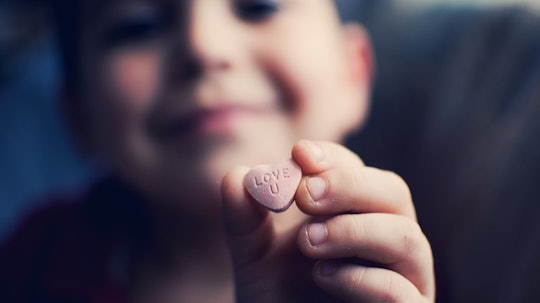 A boy holds up a candy heart