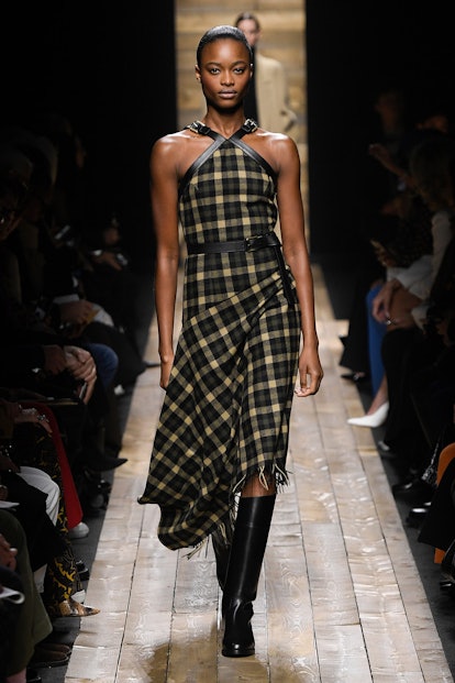 The model wears a black-and-beige checkered dress with a halter neck by Michael Kors.