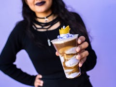 A woman dressed in all black holds up the Poor Unfortunate Souls drink at the Disney After Hours eve...