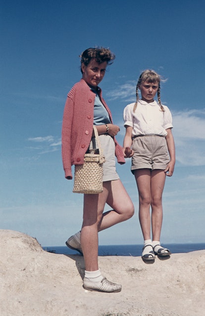 A mother and daughter standing on a beach in a vintage photo
