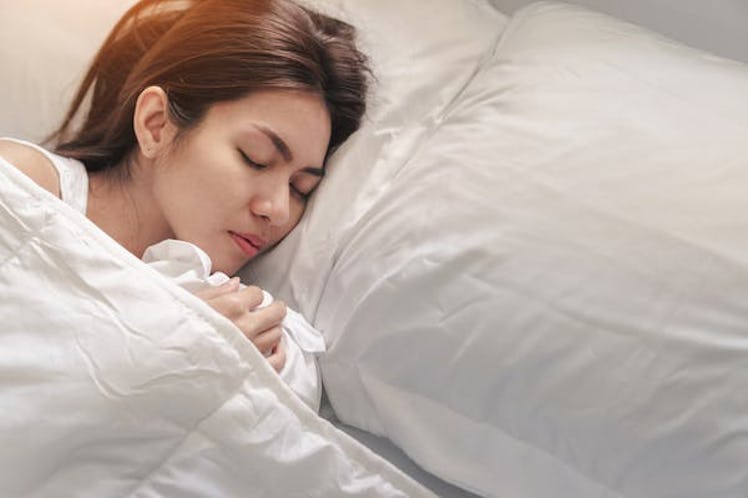 Young asian woman sleeping alone on white pillow on bed in bedroom on morning time, copy space.