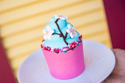 A cherry blossom-themed cupcake with blue icing sits on a plate at Disney for Valentine's Day. 
