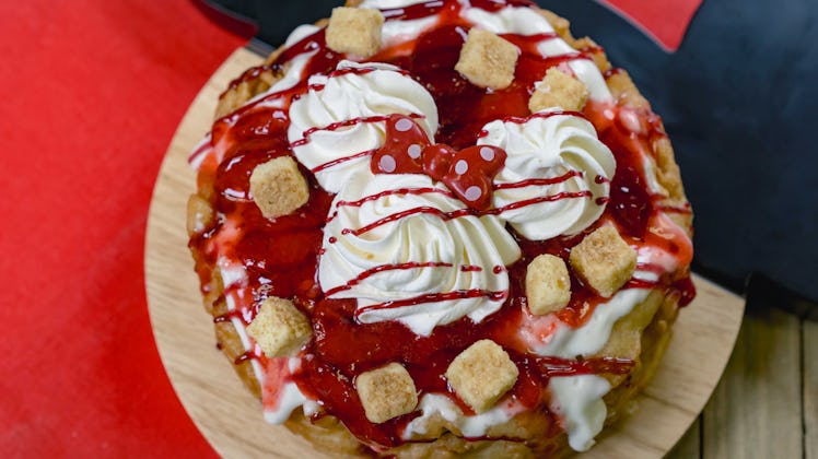 Minnie Mouse-shaped whipped cream sits on top of a strawberry cheesecake funnel cake available at Di...