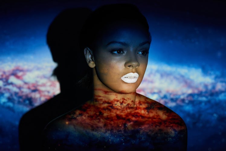 Young black woman in front of galaxy, universe background