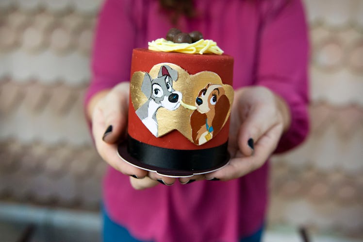 A woman holds out a 'Lady and the Tramp' cake for Valentine's Day at Disney. 