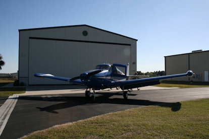 An airplane sits out in front of an airplane hangar available for rent on Airbnb.