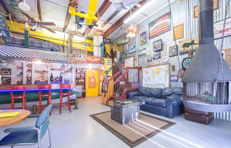 A decorated airplane hangar has pictures of airplanes on the wall and is listed on Airbnb. 