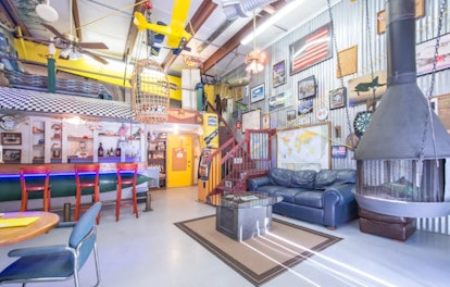 A decorated airplane hangar has pictures of airplanes on the wall and is listed on Airbnb. 
