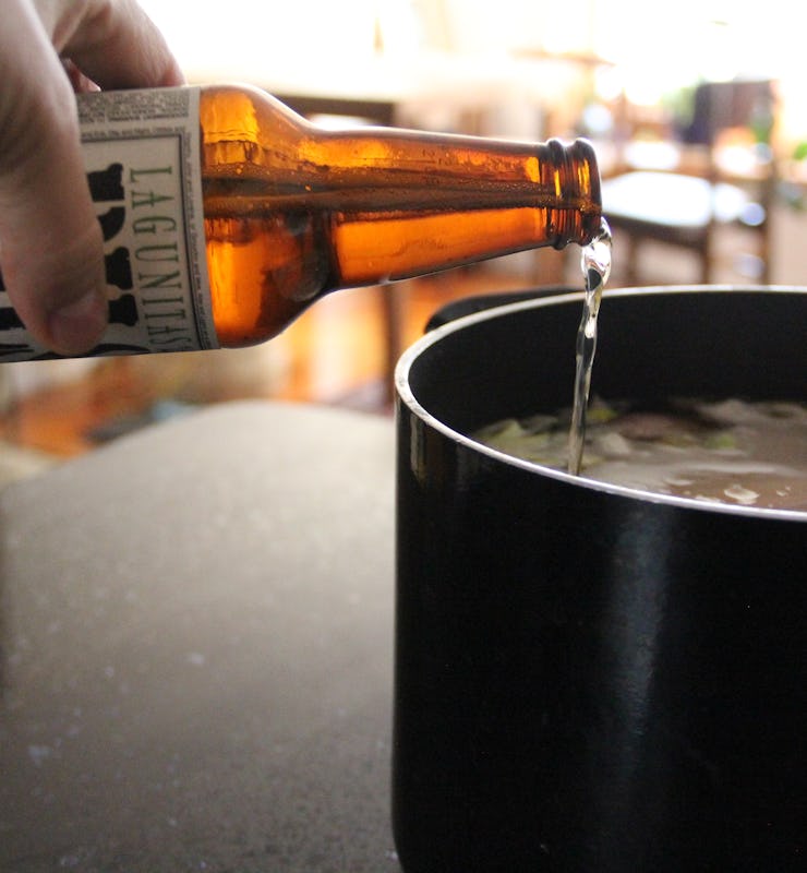 A person pouring beer in a large black pot