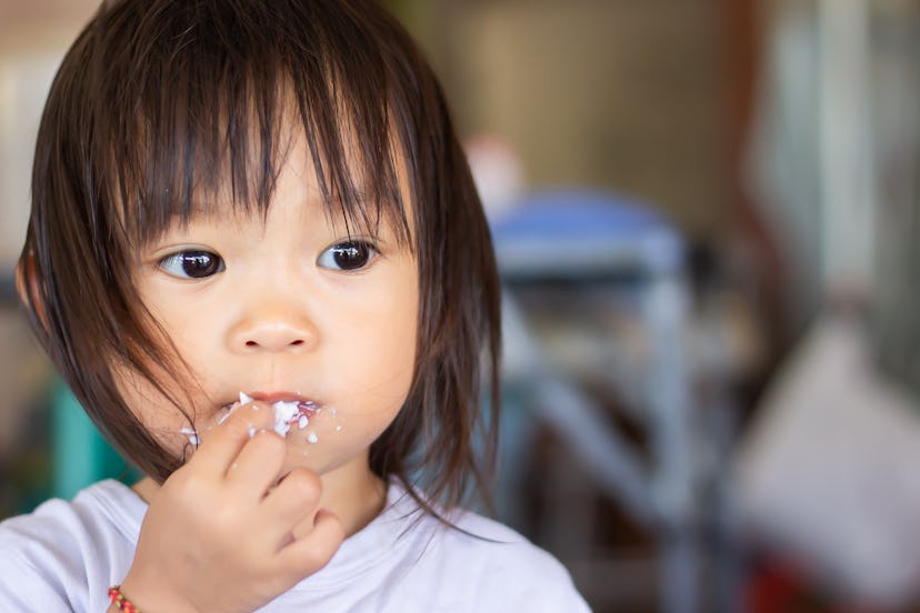 Happy​ Asian​  girl​ eating​ rice and​ eggs with her fingers.