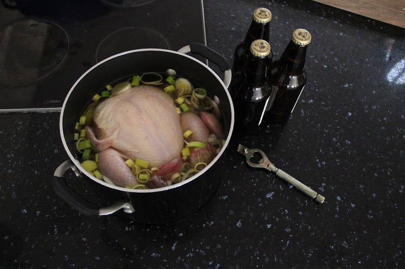 Chicken and onions in the pot next to three bottles of beer