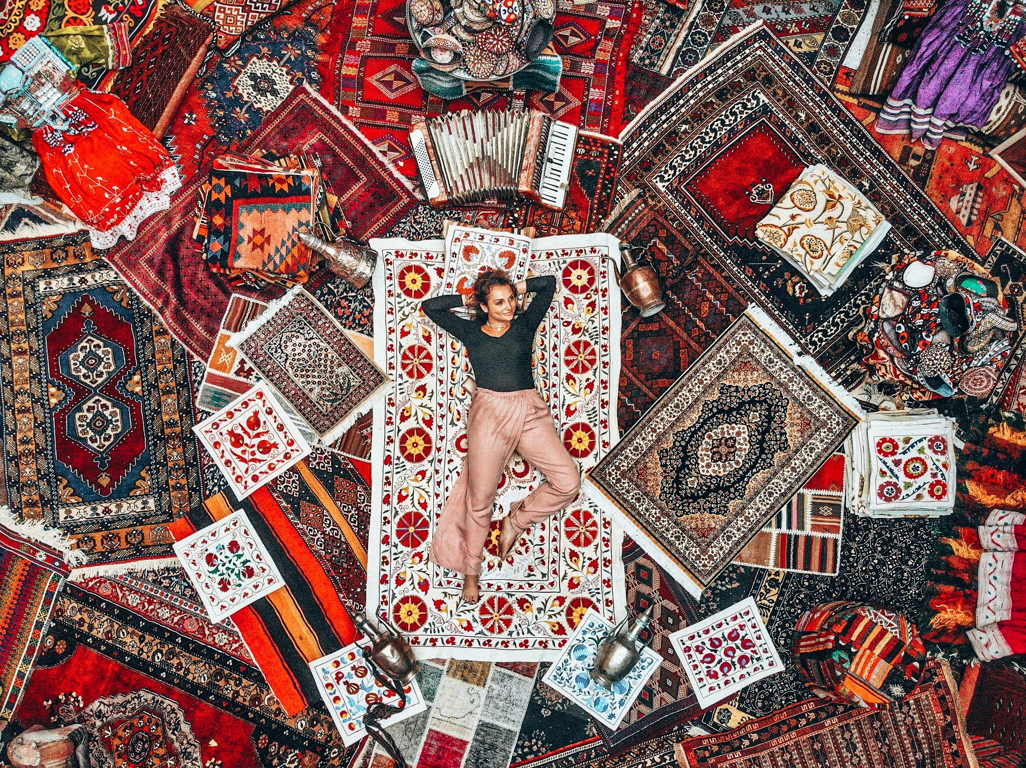 A woman lounges on a bunch of colorful rugs at a rug store in Cappadocia, Turkey.
