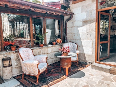 The exterior of the Star Cave Hotel in Cappadocia, Turkey features vintage chairs, a colorful rug, a...