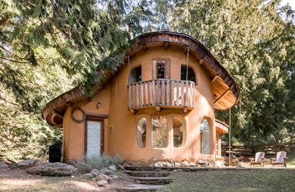 An orange cottage on Mayne Island is tucked into the woods and a short walking distance away from th...