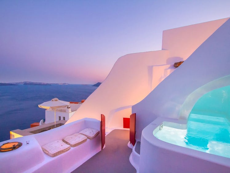 The Hector Cave House in Santorini, Greece glows in purple and pink during a nightly sunset.