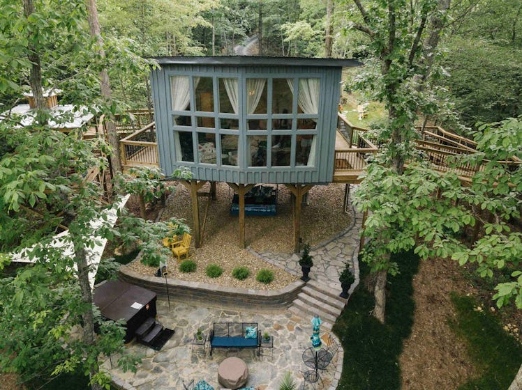 This treehouse in Tennessee has a large window, patio with a hot tub, and is available to rent on Ai...