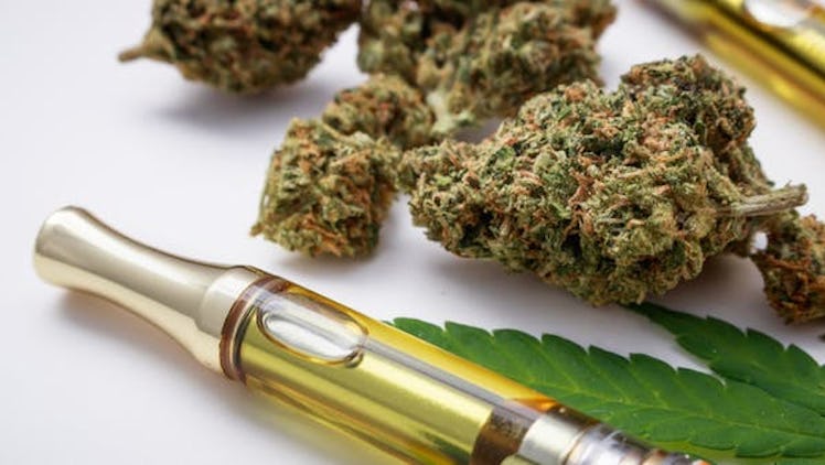 Marijuana buds closeup with cannabis oil vape and leaf.