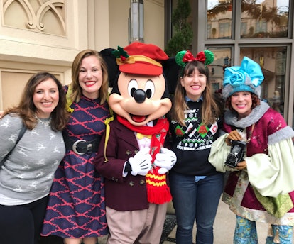 A group of friends pose and smile with Mickey Mouse at Disneyland. 