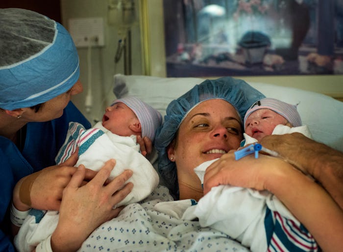 A couple hold their twins shortly after birth in hospital