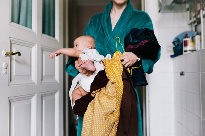 Woman holds baby and laundry pile