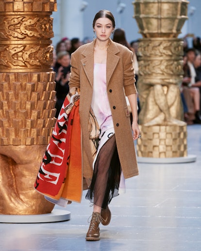 A model in a brown coat and a pink sheer dress walks the runway at chloe's fall 2020 show