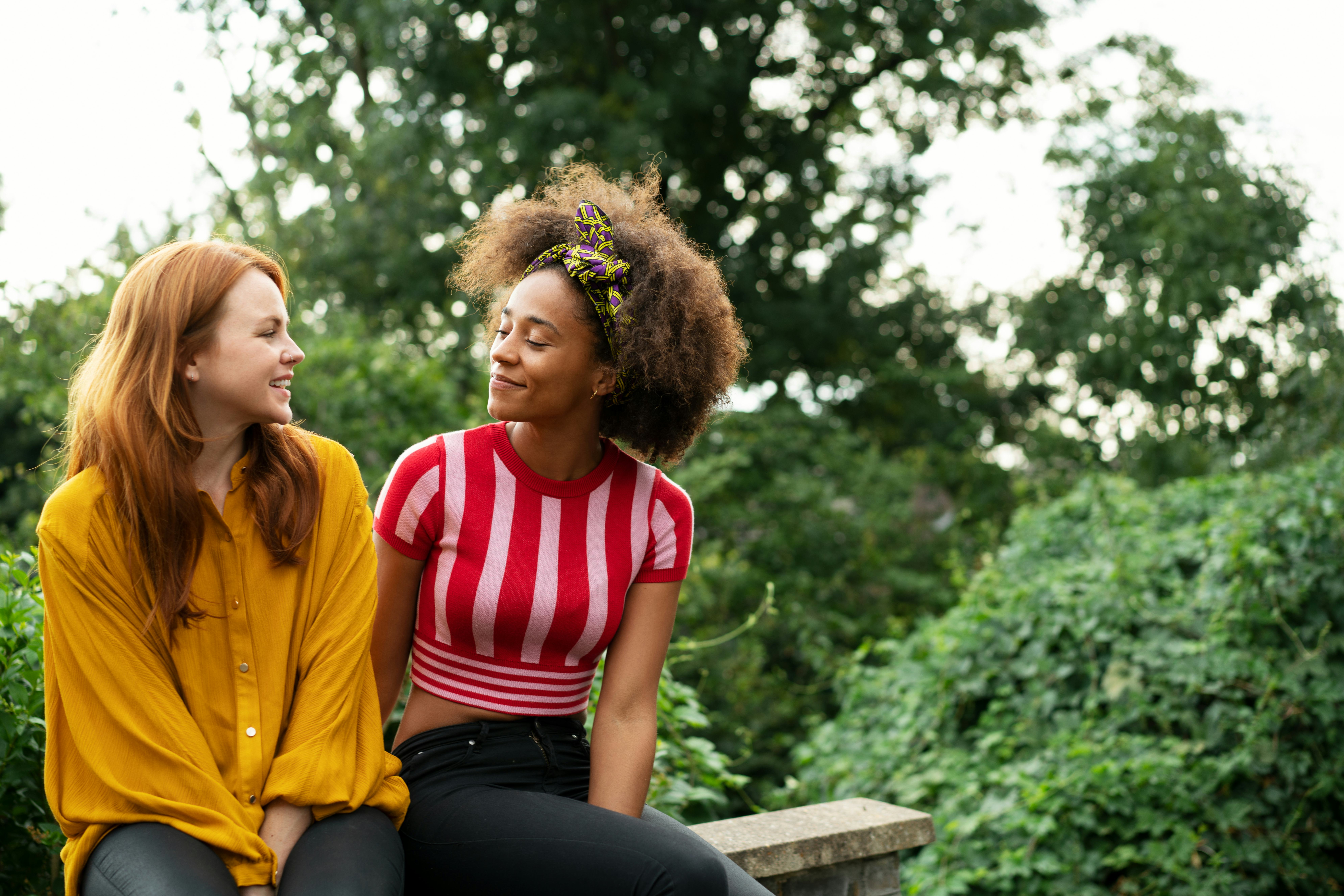Biracial lesbian couple sitting on wall